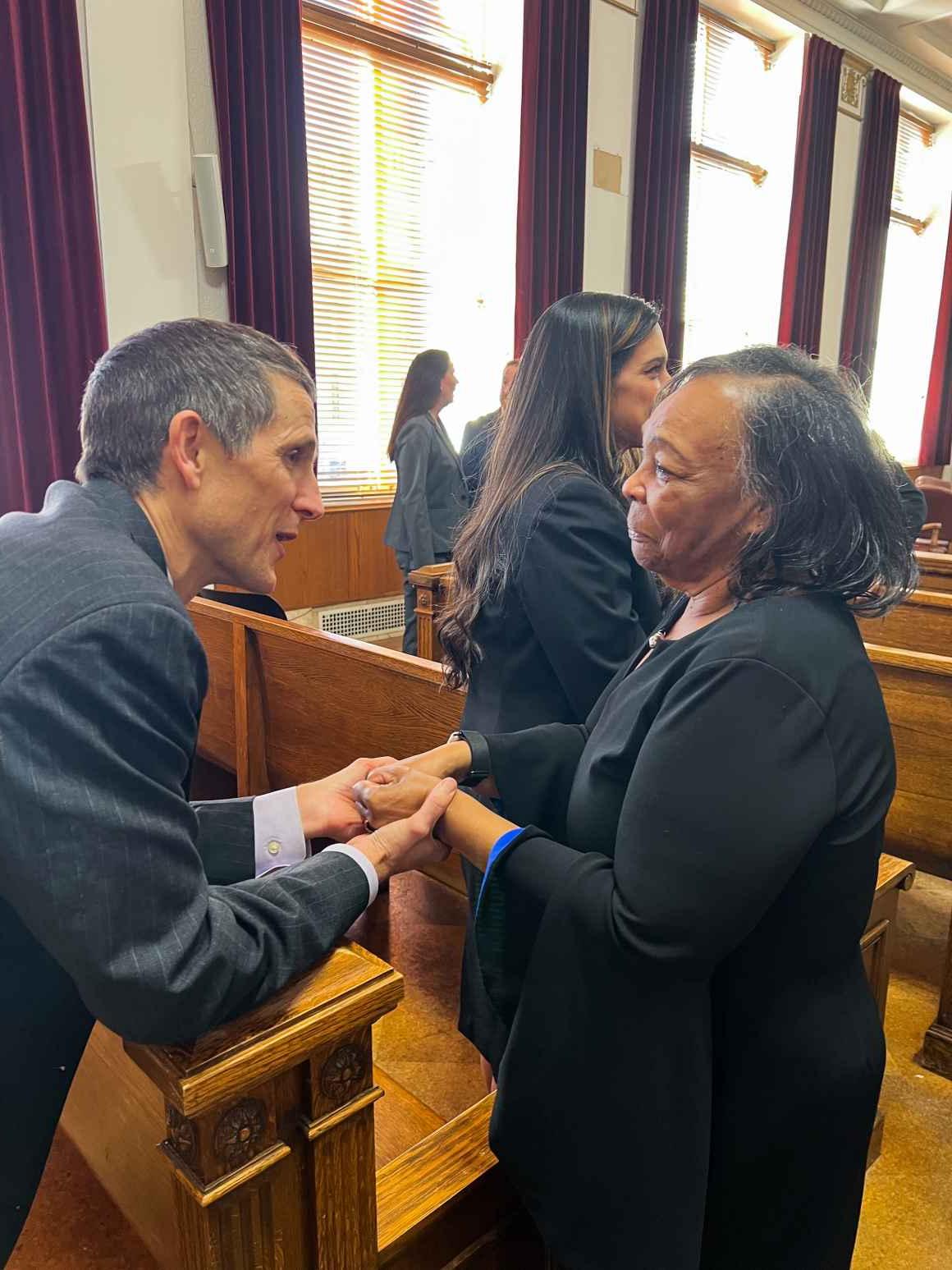 Photo of Ruby Johnson and ACLU of Colorado legal director Tim MacDonald shaking hands in a Denver courtroom